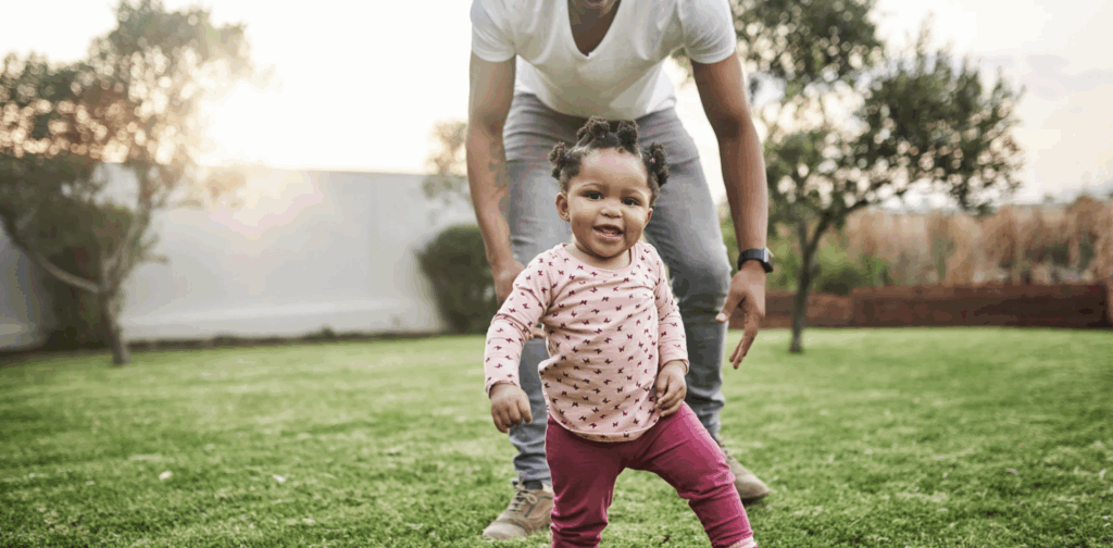 Father and toddler playing in grassy yard, illustrating joyful family moments related to adoption and creating a loving home.