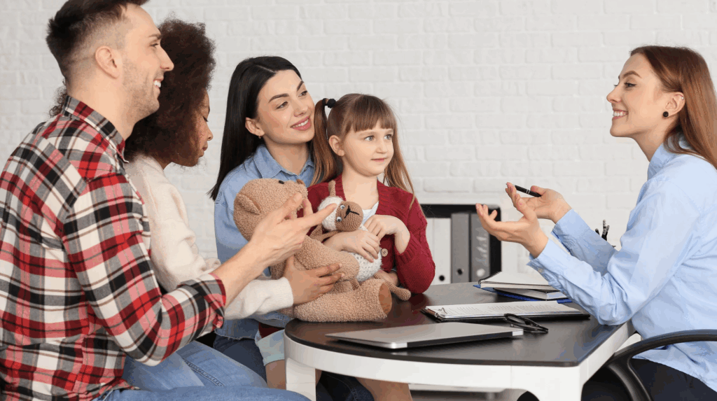 Family consultation about adoption process, featuring a smiling couple with a child holding a teddy bear, discussing with a legal advisor in an office setting.