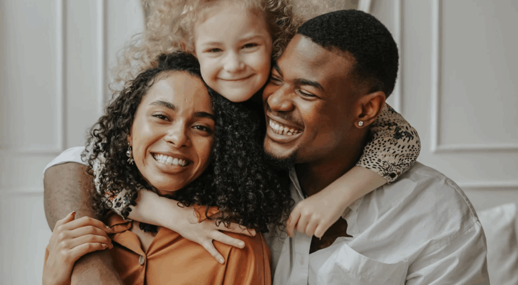 Smiling family portrait of a mother, father, and daughter celebrating together, representing joy and love in the context of adoption.
