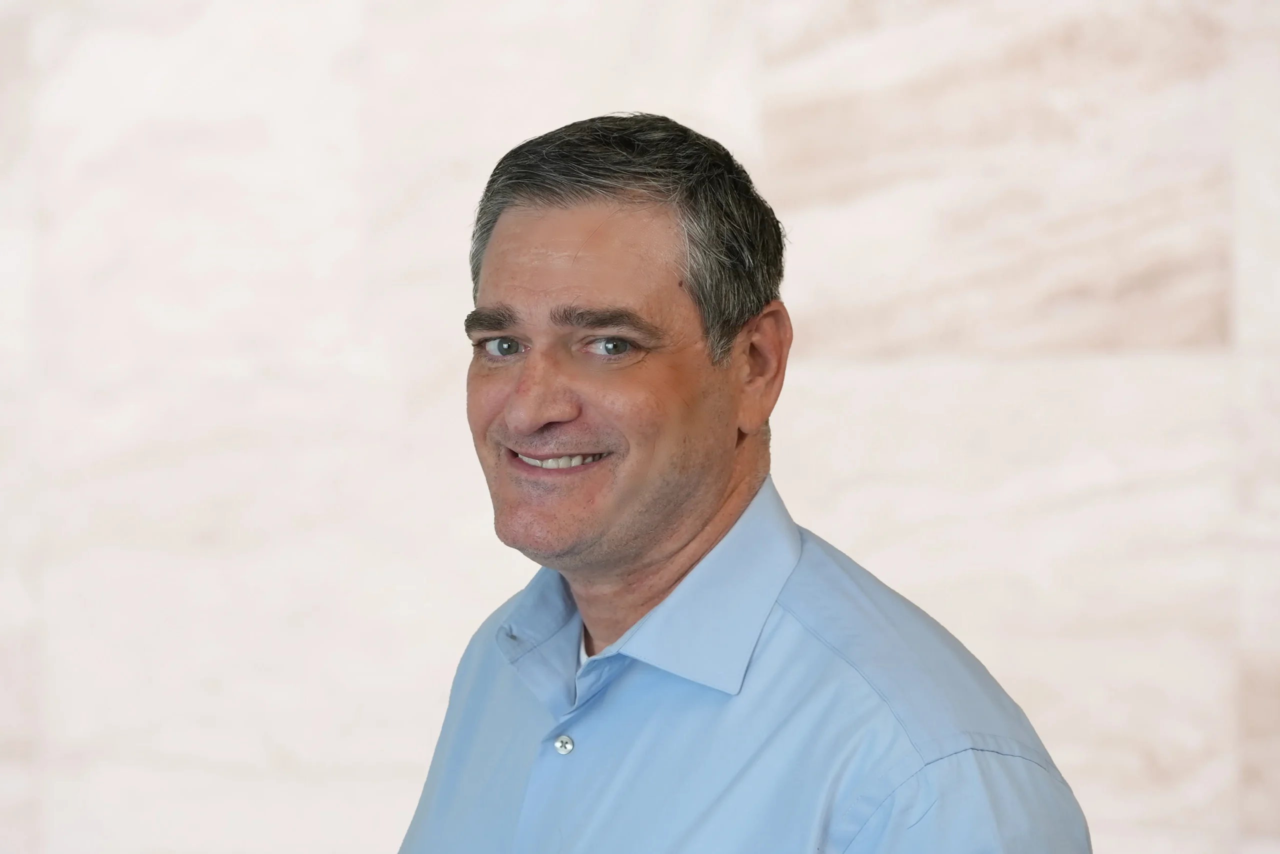 Eric Engel, attorney at Law Office of Bryan Fagan, smiling in a blue shirt, professional headshot, Dallas office setting.