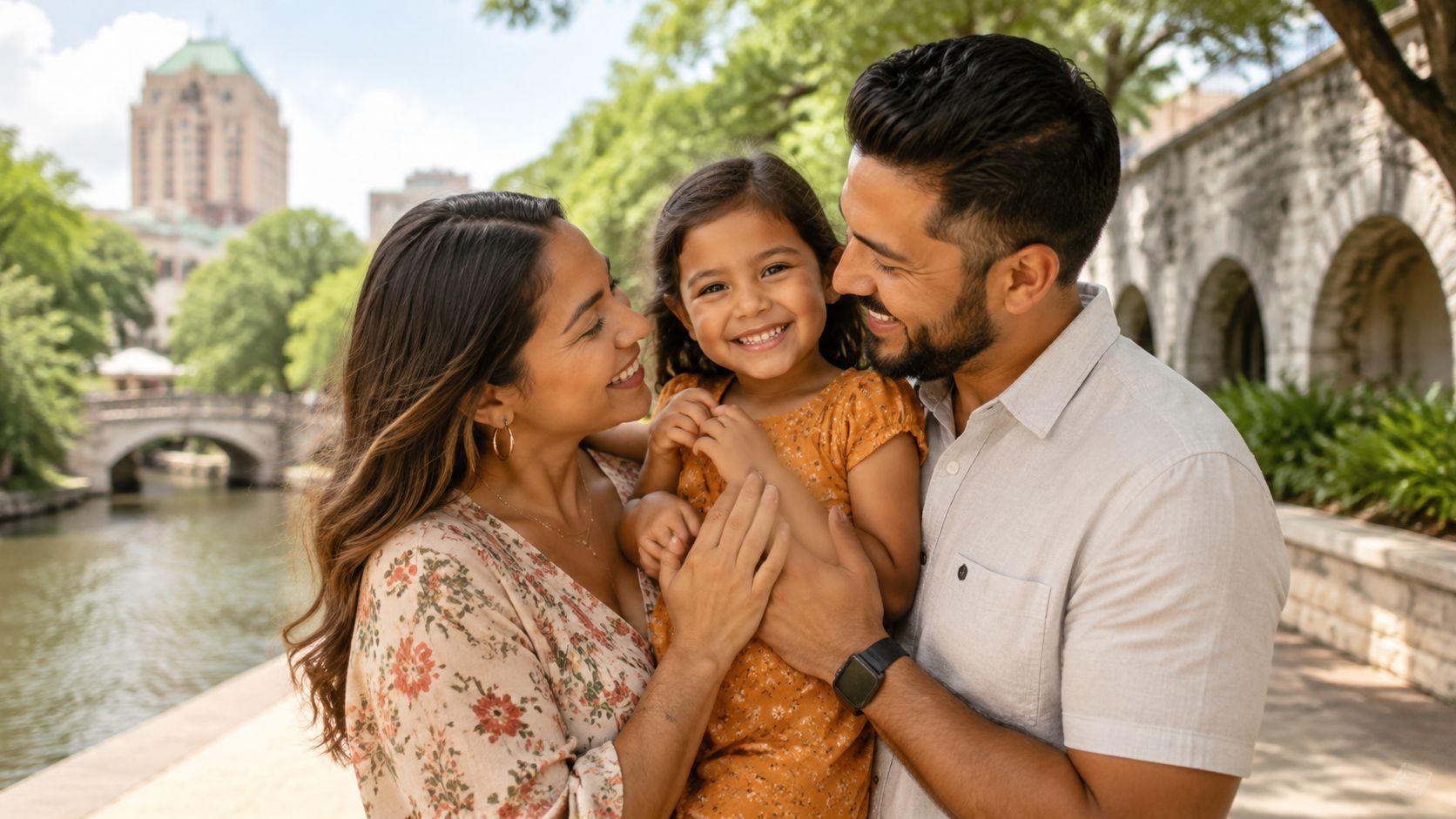 A happy Hispanic family posing together along the scenic San Antonio River Walk during a sunny day.